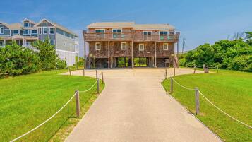 A two-story building with a central entrance, surrounded by a grassy area and a pathway leading to it.