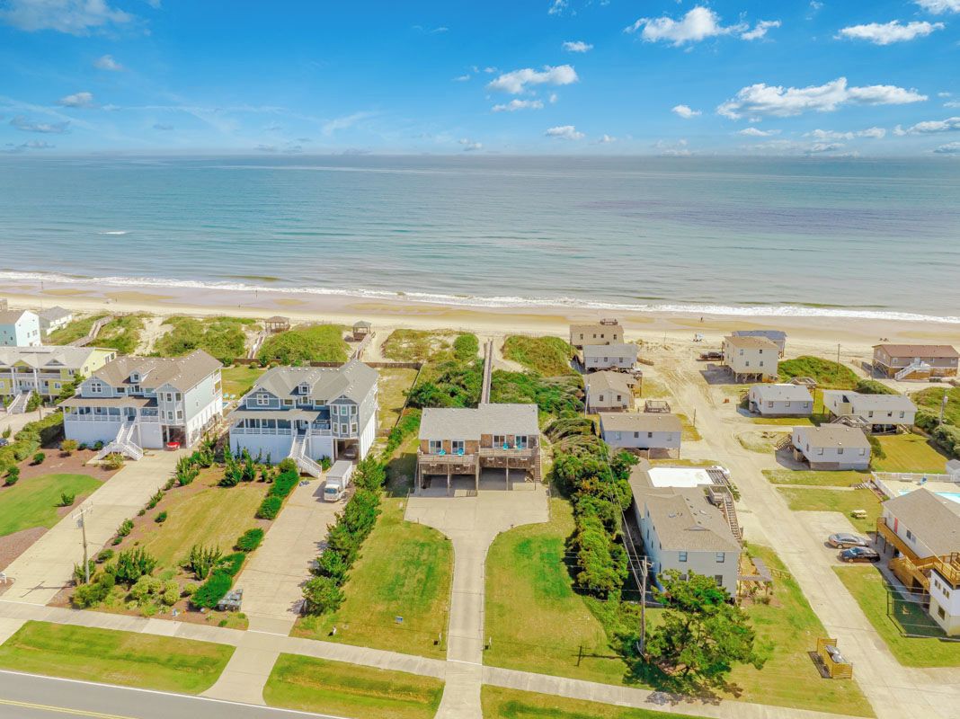 A residential area with houses, a beach, and a clear sky.