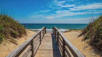 A wooden boardwalk leading to a beach with dunes on either side.