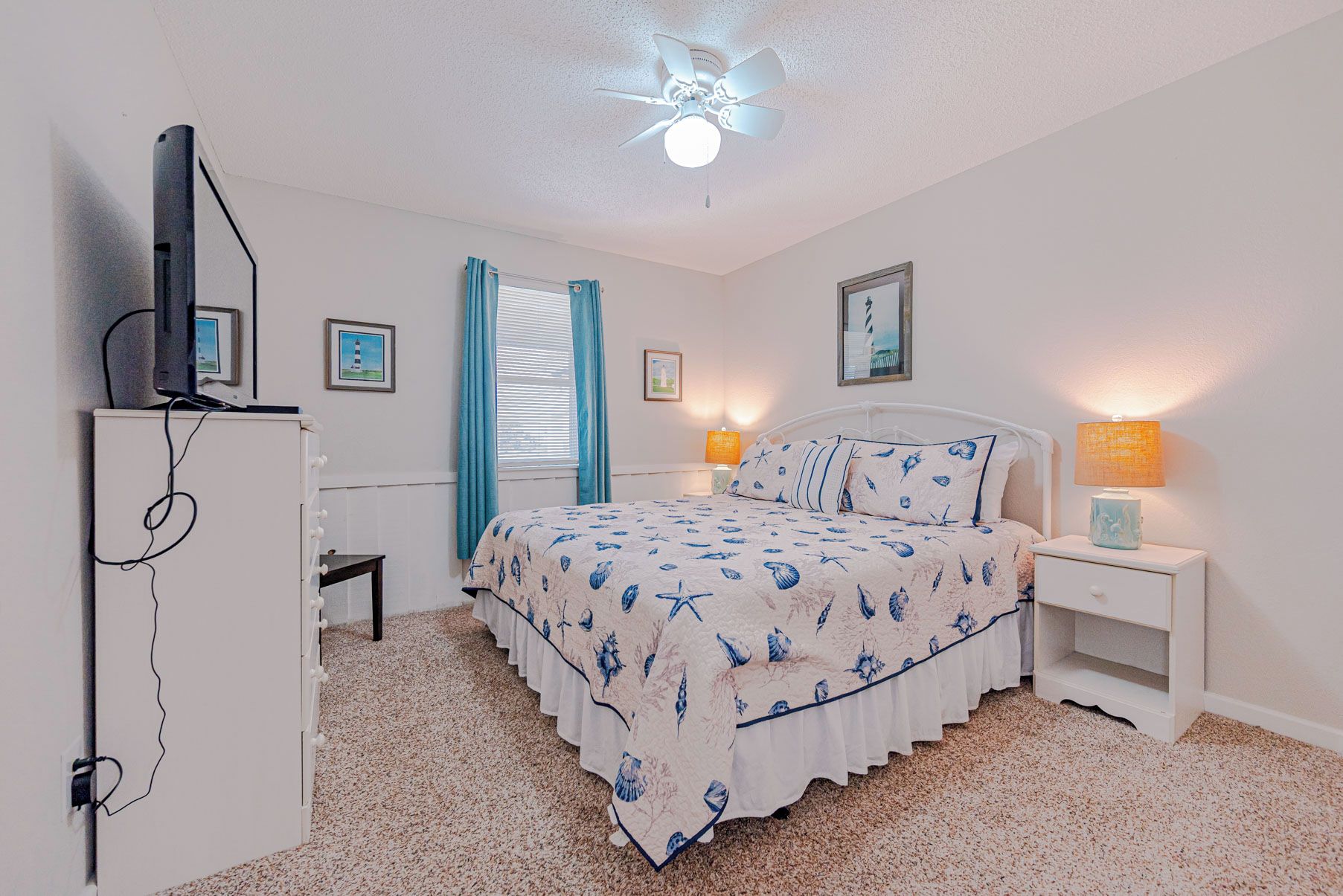 A bedroom with a bed, bedside tables, a ceiling fan, and a television on a stand.