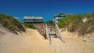 A wooden boardwalk leading to a beachfront property with multiple buildings.