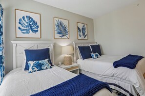 Ein Hotelzimmer mit zwei Betten, einem Nachttisch und Wandbildern.