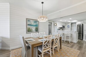A dining area with a wooden table, white chairs, and a hanging light fixture. - Gorgeous Oceanfront Villa w/ Amenities (Hilton Head Island)