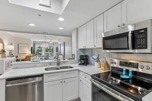 A modern kitchen with stainless steel appliances, white cabinetry, and a built-in oven. - Gorgeous Oceanfront Villa w/ Amenities (Hilton Head Island)
