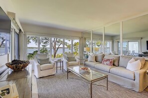 Ein modernes Wohnzimmer mit großem Fenster, einer Couch, einem Couchtisch und einer Zimmerpflanze.