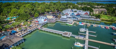 An aerial view of a marina with boats docked, a pier, and a building with a blue roof.