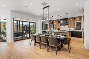 A modern kitchen with a dining area, wooden flooring, and large windows. - Mountain Luxury Lodge w/Gondola Access 1099 (Steamboat Springs)