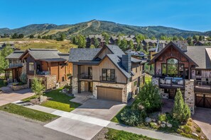 A modern multi-story house with a stone facade, large windows, and a spacious front yard. - Mountain Luxury Lodge w/Gondola Access 1099 (Steamboat Springs)