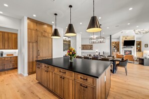 Une cuisine moderne avec des meubles en bois, un plan de travail noir et des luminaires suspendus.