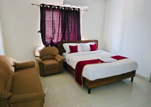A bedroom with a bed, a chair, and a window with curtains. - Deluxe Srinivasa Home Stays (Hyderabad)