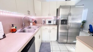 Een moderne keuken met roestvrijstalen apparatuur, een magnetron en een vaatwasser.