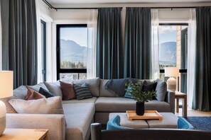 A modern living room with a sectional sofa, a coffee table, and a potted plant. - 2 Turns - Revelstoke Vacations (Revelstoke)