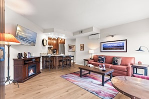 A modern living room with a fireplace, a dining area, and a kitchen in the background. - Main Street Condo - Walking Distance to Town Lift | Managed by Park City Lodging (Park City)