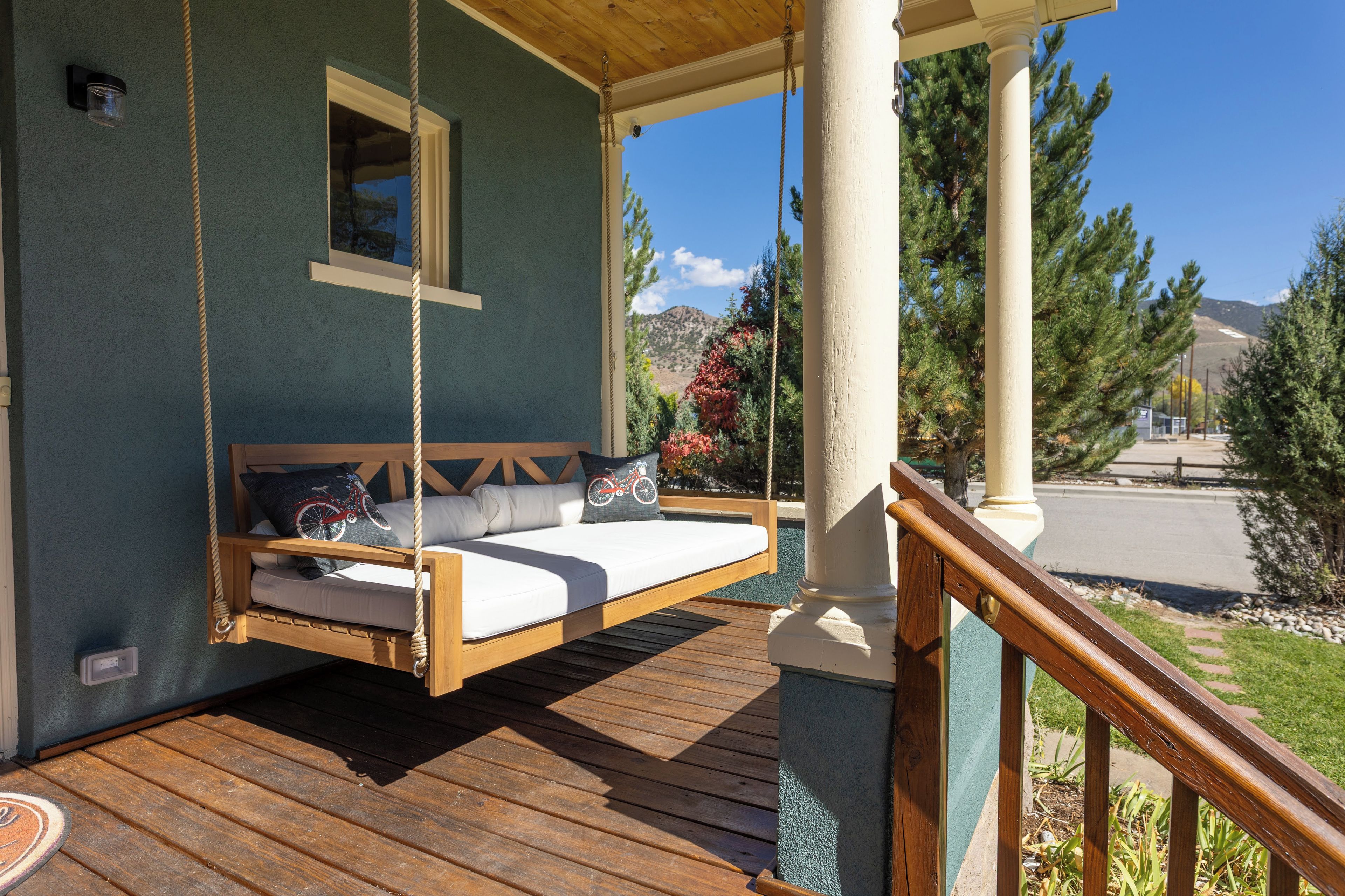 Terraza de madera con hamaca y barandilla, con vista a un paisaje montañoso.