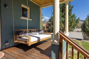 Terraza de madera con hamaca y barandilla, con vista a un paisaje montañoso.