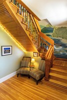 Una escalera de madera con un cuadro de un paisaje en la pared.