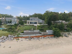 Une propriété située sur la côte, comprenant une grande maison, une piscine et un espace de plage.