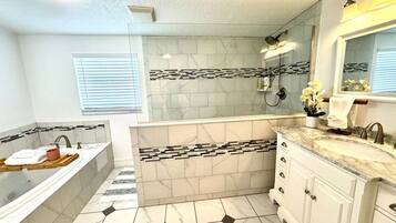 Une salle de bain comprenant une baignoire, un meuble-lavabo et un espace douche.
