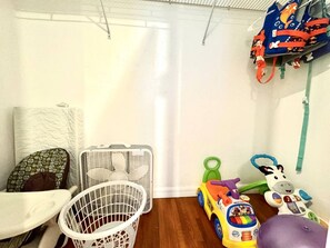 Un'area giochi per bambini con giochi, un cesto bianco e una carrozzina.