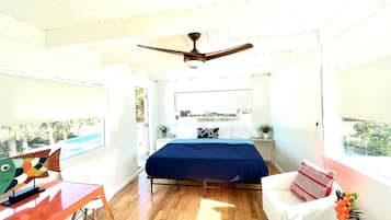 A modern bedroom with a bed, a desk, a chair, and a ceiling fan.