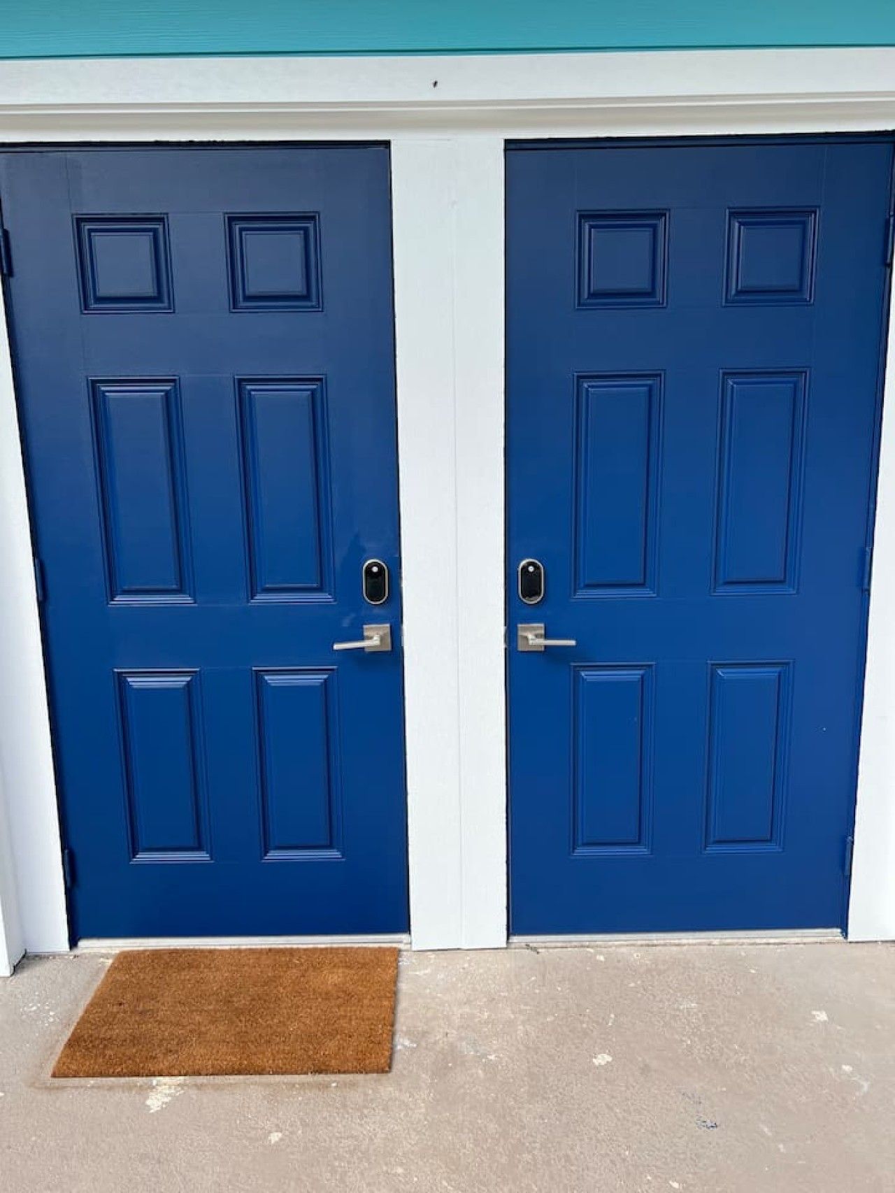 Dos puertas azules con molduras blancas, cada una con cerradura y pomo.