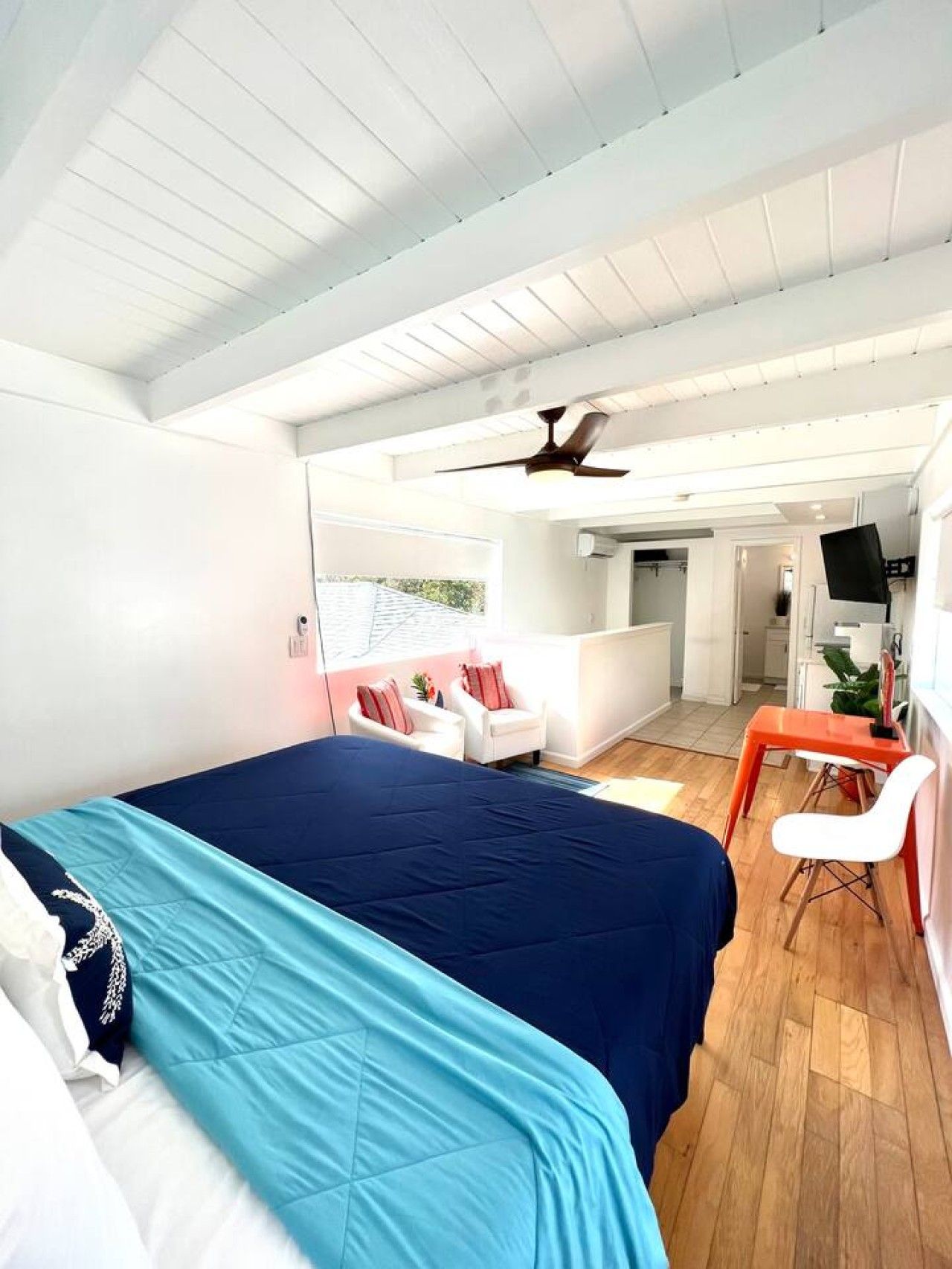 Una habitación con cama, una silla, una mesa y un ventilador de techo.