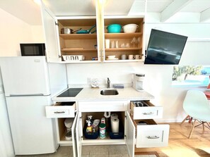 Una cucina compatta con forno a microonde, lavandino e pensili.