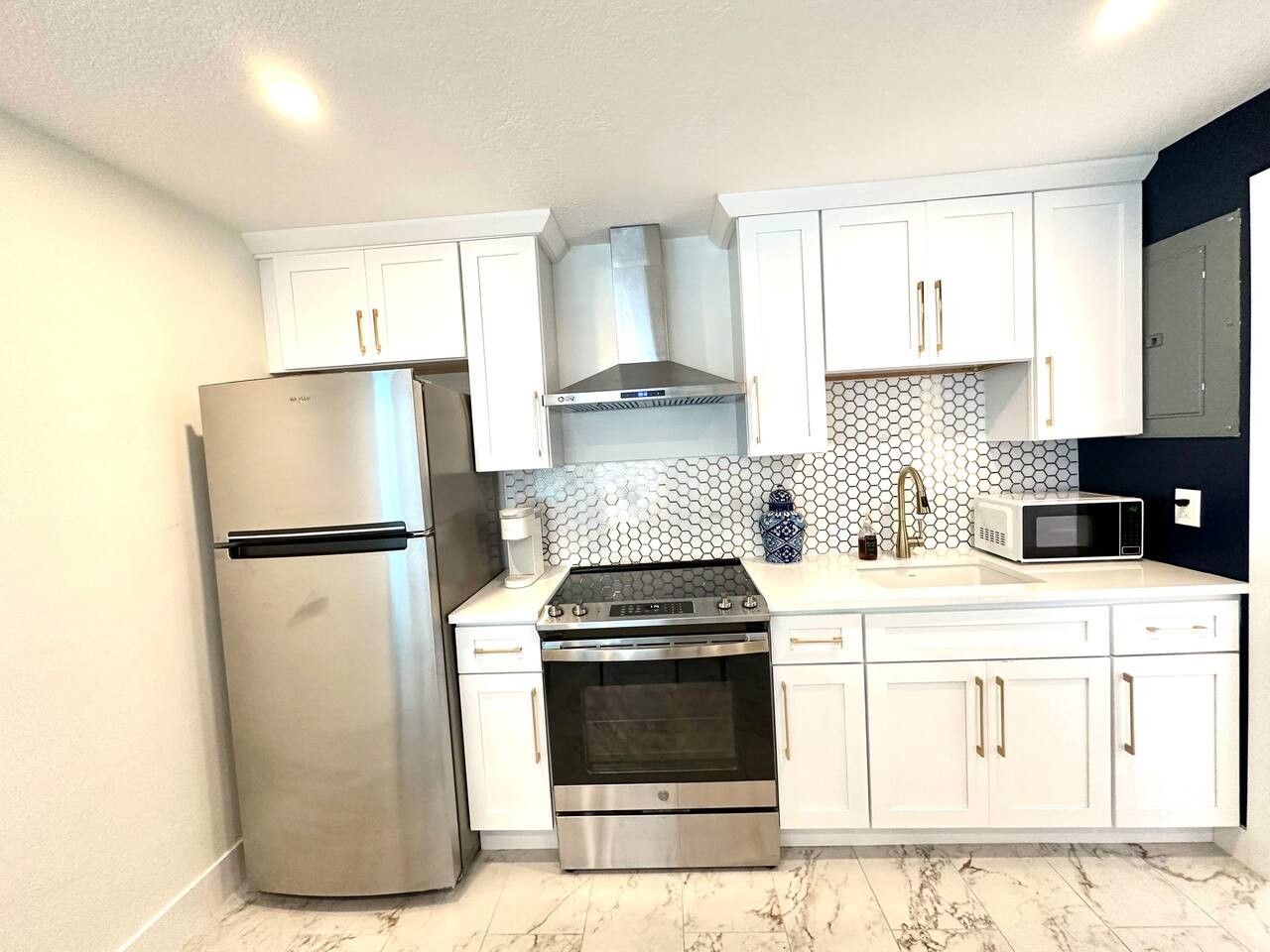 A kitchen with white cabinets, a stainless steel refrigerator, a stove, an oven, and a microwave.