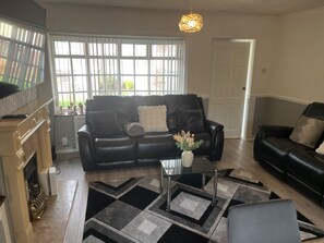 Ein Wohnzimmer mit einem schwarzen Ledersofa, einem Glastisch und einem Kamin.