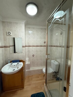 Ein Badezimmer mit Waschbecken, Spiegel, Toilette und Duschkabine.