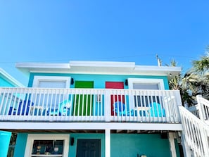 Un immeuble de deux étages doté d’un balcon, d’une porte verte et d’une porte rouge.