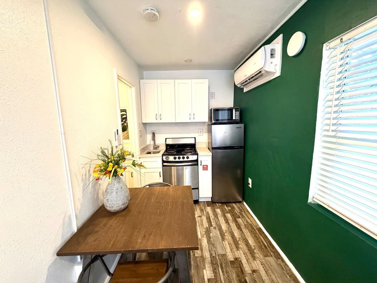 Una cocina compacta con armarios blancos, un microondas, una estufa y un refrigerador.