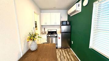 Una cocina compacta con armarios blancos, un microondas, una estufa y un refrigerador.