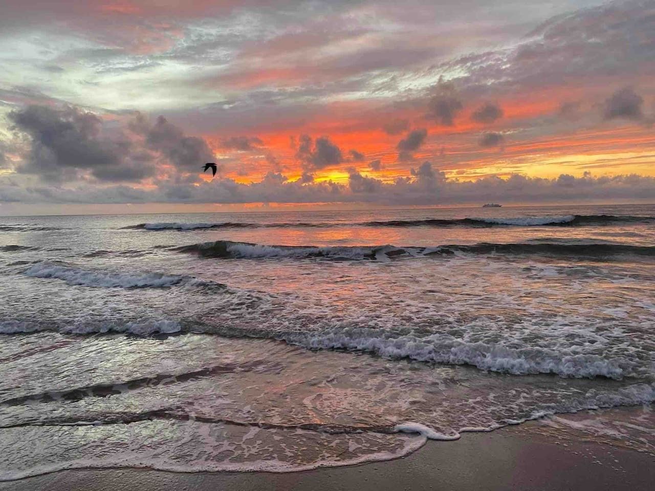 Una playa con olas y un atardecer.
