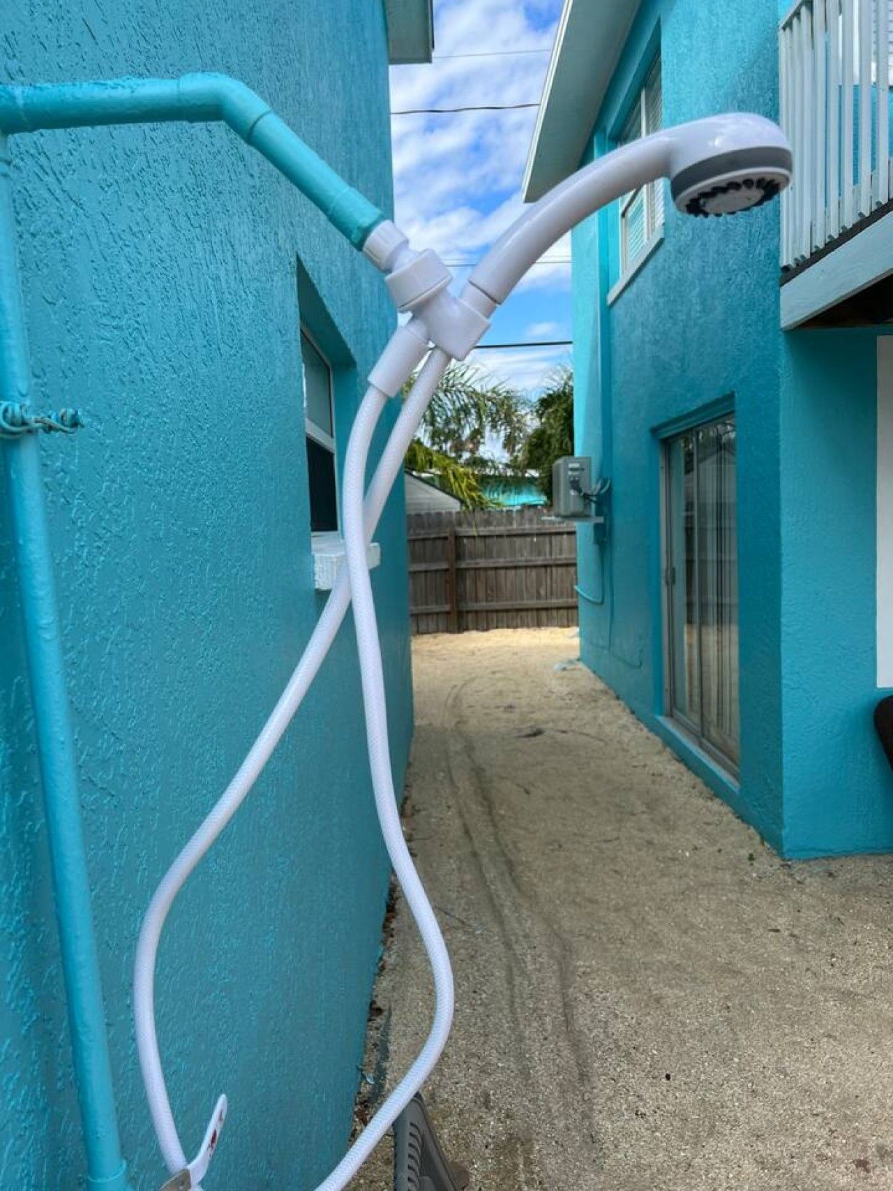 A blue building with a white hose connected to a white showerhead.