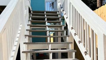 Una escalera de madera con barandas blancas que conduce a un edificio de fachada azul.
