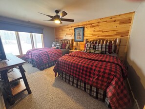 A room with two beds, a ceiling fan, a wooden wall, and a window. - Secluded 5-BR Wooded Cabin Retreat with Panoramic Views in Vanderbilt (Vanderbilt)