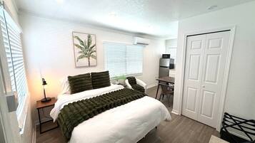 A bedroom with a bed, bedside table, lamp, and a door.