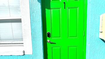 A bright green door with a keypad lock, a window with blinds, and a mailbox on the wall.