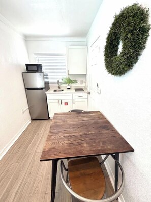 Une cuisine de taille réduite, avec une table en bois, un réfrigérateur et un four à micro-ondes.