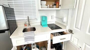 A compact kitchen with a sink, countertop, and storage cabinets.