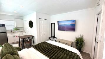 Una habitación de hotel moderna con una cama, un escritorio, un televisor y vistas al exterior.