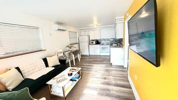 A living room with a sofa, coffee table, and a TV mounted on a yellow wall.