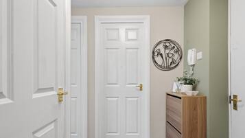 A hallway with a white door, a wooden cabinet, and a wall-mounted telephone.