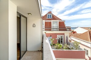 A balcony with a view of a building with red-tiled roofs and a clear sky. - Bairro Alto Modern W Terrace AND Garage by Homing (Lisbon)