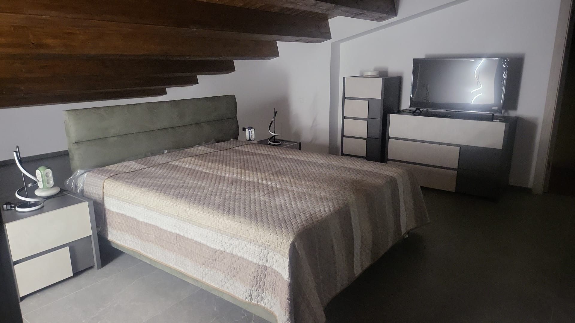 Una camera da letto moderna con un letto, comodini, TV e un armadio.