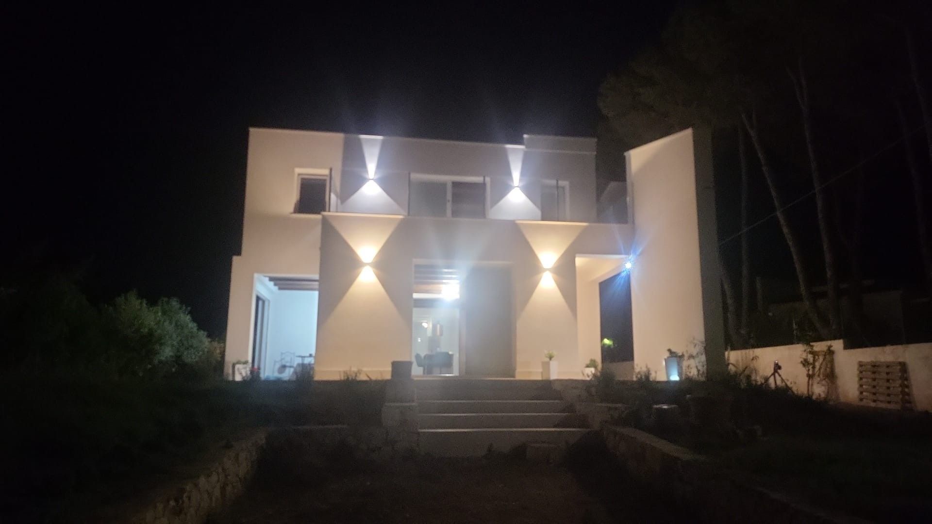 Edifício moderno com fachada simétrica, iluminado por iluminação externa.