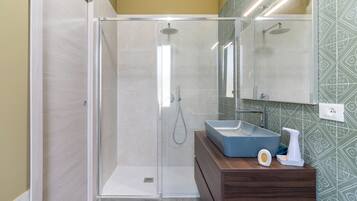 A modern bathroom with a glass-enclosed shower, a wooden vanity, and a patterned wall.