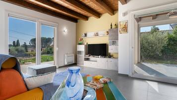 Un soggiorno moderno con un grande televisore, un tavolo da pranzo e vista sull'esterno.
