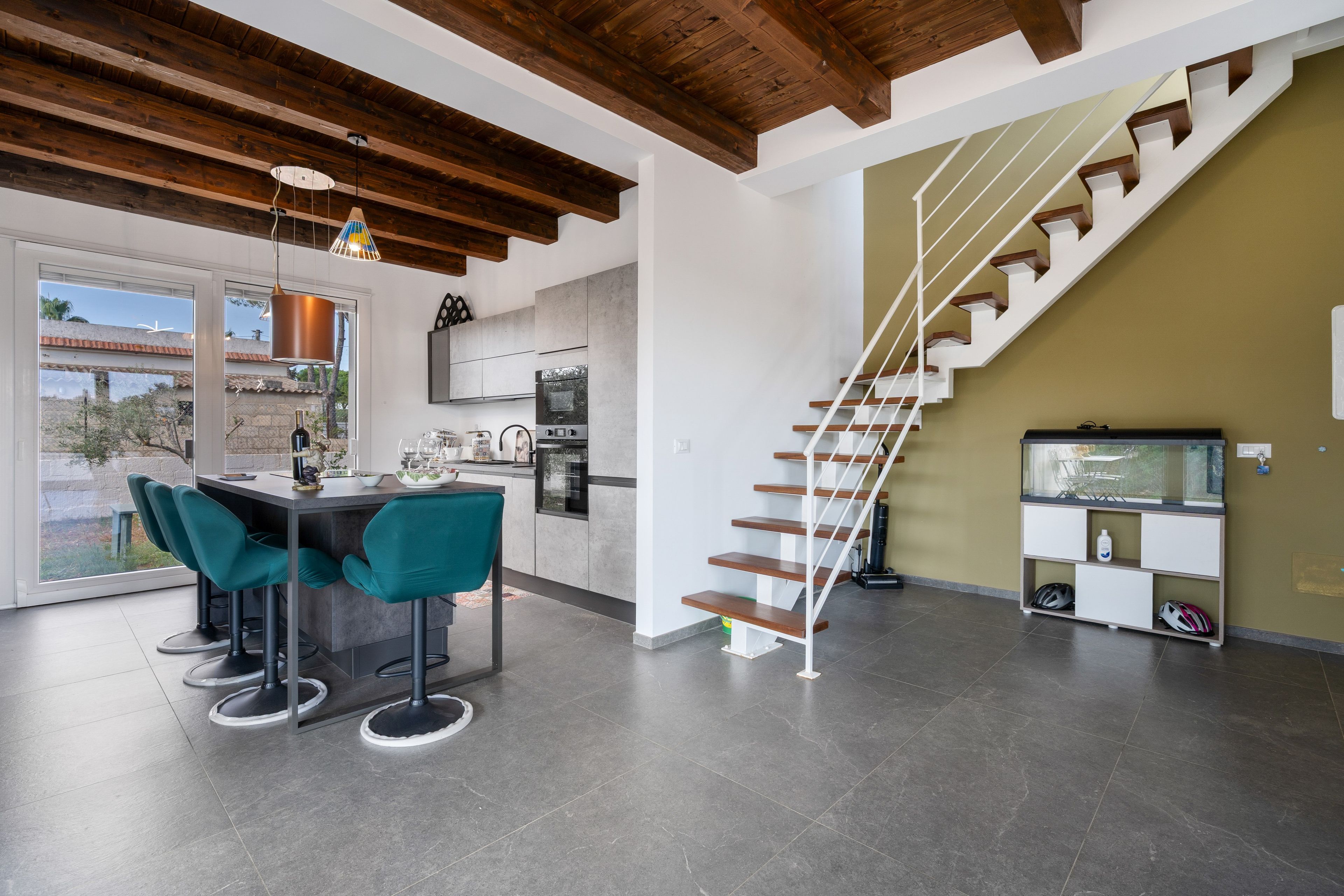 Eine moderne Küche mit Essbereich, einer Treppe und Blick ins Freie.